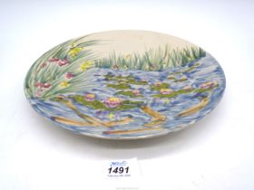 A Cobridge stoneware Charger with scene of reeded pond with water lilies and goldfish, 11" diameter.