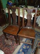 A pair of Oak country Side Chairs having solid seats and carved details to the front including to