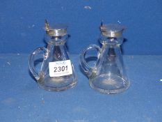 A pair of small glass Whisky Jugs for nightcaps, Birmingham 1913 silver rims and lids,