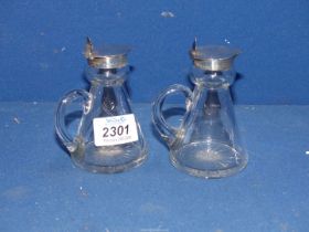 A pair of small glass Whisky Jugs for nightcaps, Birmingham 1913 silver rims and lids,