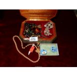 A musical jewellery box containing brooches, necklaces, pin badges,
