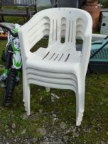 Four white stacking patio chairs.