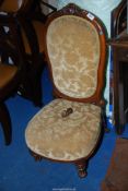 A circa 1900 Mahogany framed nursing chair standing on turned and fluted front legs and upholstered