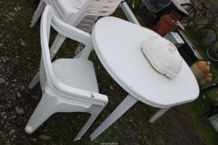 White patio table, two chairs and parasol base.