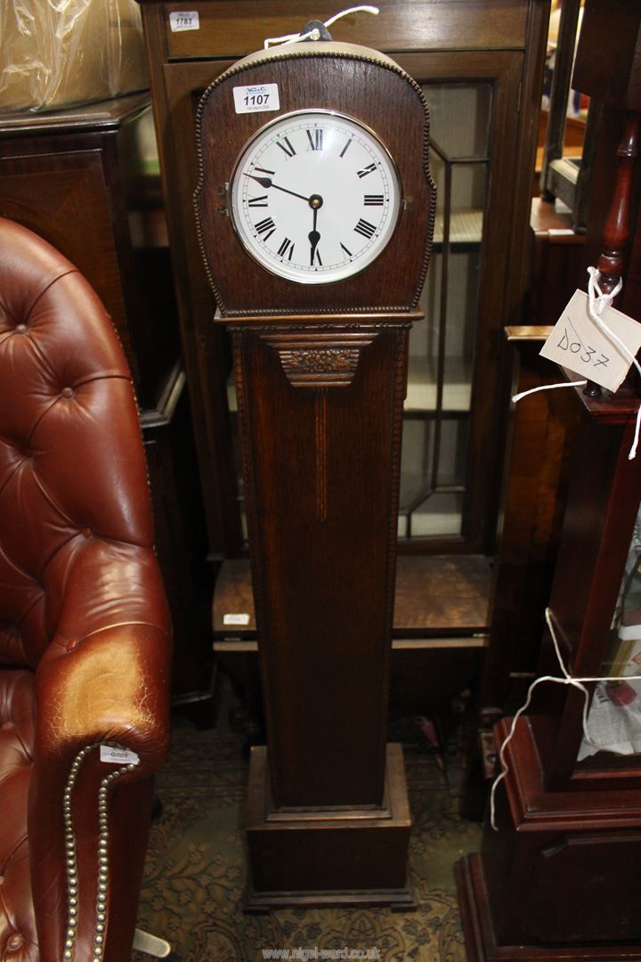 An Oak cased Grandmother Clock, the white face with Roman numerals having a later quartz movement,