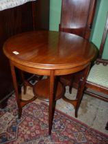 A circular Mahogany occasional table standing on shaped legs united by a lower shelf,