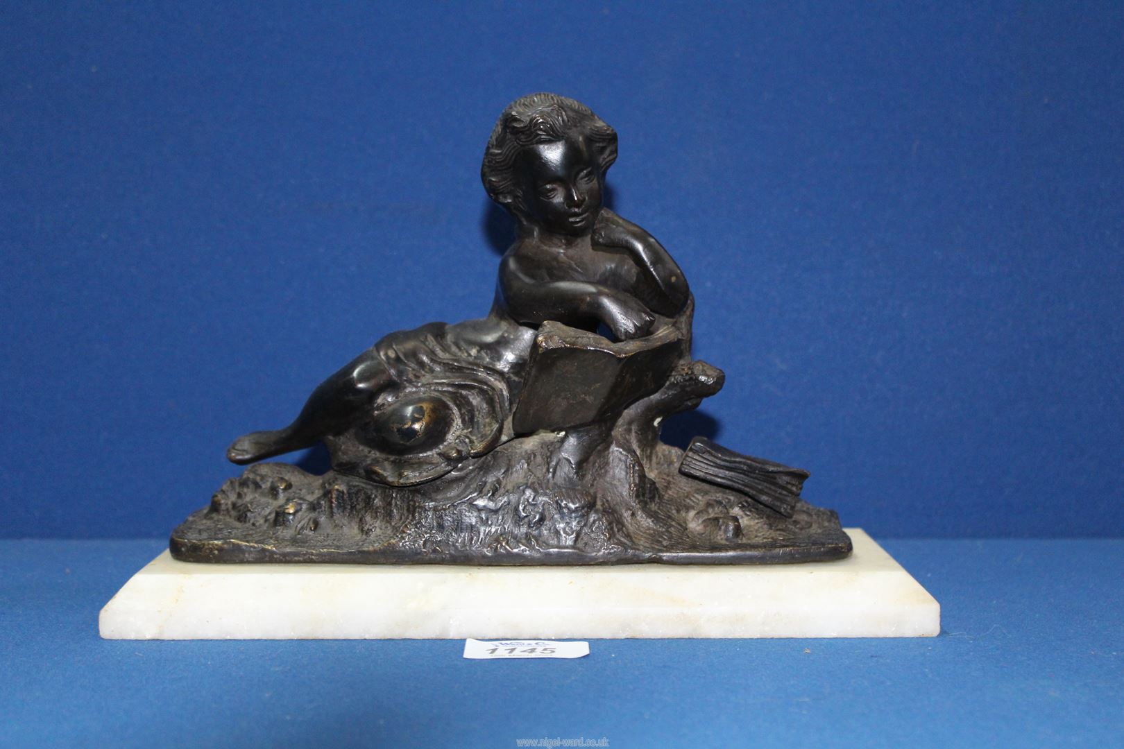 A 19th century bronze of a reclining figure reading,