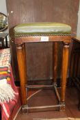 An early 20th century Mahogany framed stool standing on circular legs united by stretchers with
