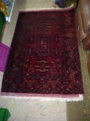 An Eastern rug, red ground with geometric patterns and borders, some wear, 61" x 40".