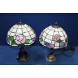 A pair of Tiffany style table lamps with stylised floral detail to the shades, each 15" tall,