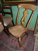 A solid Elm seated rocking Chair having a fretworked splat and turned legs.