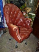 A brown buttoned brown leather upholstered high back Swivel Armchair standing on a metal base with