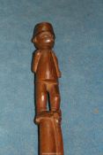 A tribal East African staff with figural pommel and tapering cylindrical shaft carved in relief