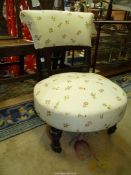 A cream upholstered circular seated low Side Chair having beige ground upholstery to the seat and