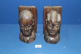 A pair of African carved hard-wood male and female heads as bookends, 8" tall.