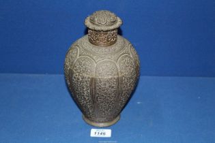 An antique bronze lidded jar, 9 1/2" tall, profusely decorated with panels of vines and flowers,