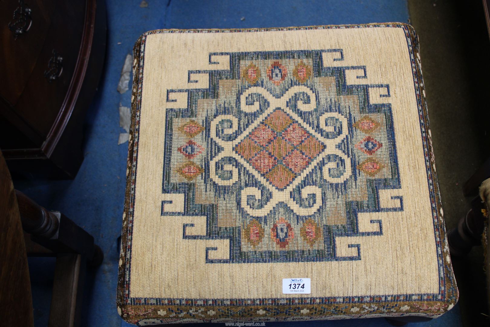 A contemporary square low Stool standing on cabriole legs and with beige ground fabric top