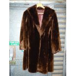 A dark brown fur coat with large buttoned cuffs and deep shawl collar.