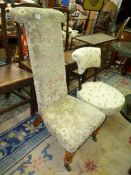 A beige and green upholstered Prie Dieu Chair standing on turned front legs with brass castors.