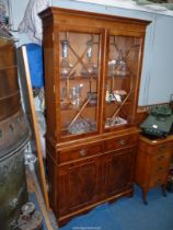 A contemporary Yew wood finished bookcase over cupboard,