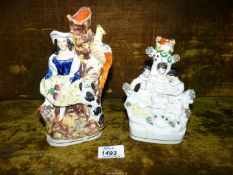 Two Staffordshire spill vases depicting three children reading a book and a girl with a dog and