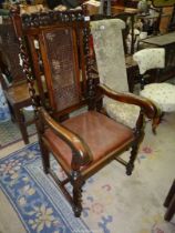 An Oak framed hall Armchair of uncommon design with cranked arm rests, caned back panel,