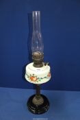 An Oil lamp with black ceramic base, milk glass reservoir with floral pattern and chimney, 26 1/2".