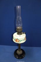 An Oil lamp with black ceramic base, milk glass reservoir with floral pattern and chimney, 26 1/2".