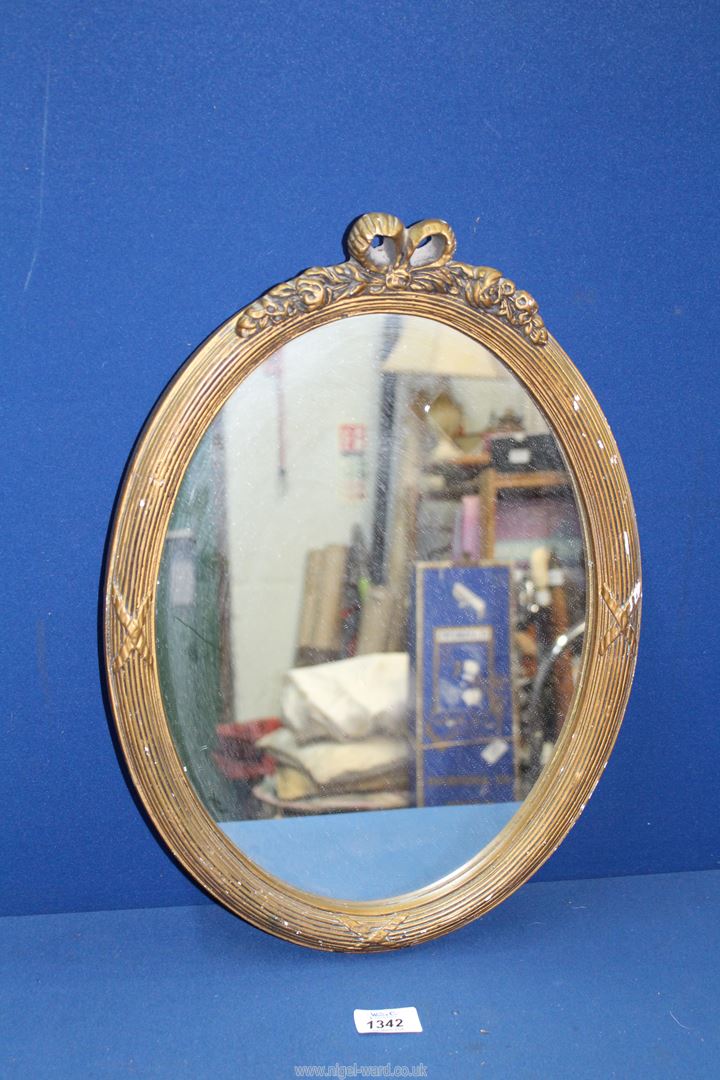 A small reeded and gilded frame oval mirror with bow pediment, 17" x 12 3/4".