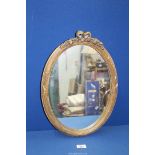 A small reeded and gilded frame oval mirror with bow pediment, 17" x 12 3/4".