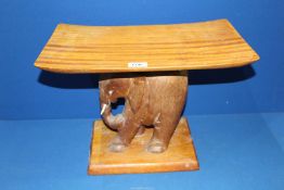 A curved top Stool with carved elephant base, 18" long x 10 1/2" wide x 12 1/2" high.