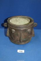 A large Persian bronze mortar, 13/14th century decorated with lugs alternating with stylized heads,