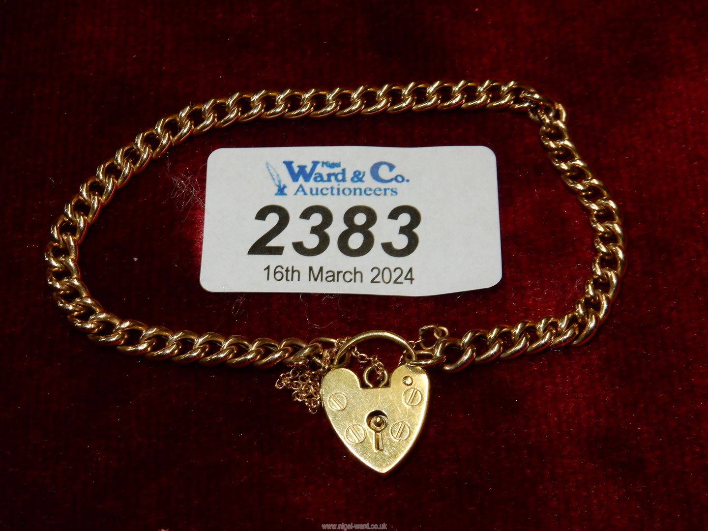 A yellow metal chain link bracelet with 18ct gold heart padlock (marked 750).