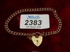 A yellow metal chain link bracelet with 18ct gold heart padlock (marked 750).