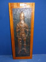 A Copper beaten image of a Knight mounted on wooden plaque, image/mount 20 1/2" x 6 1/2".