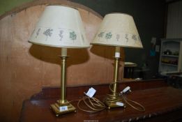 A pair of brass table lamps with shades