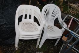 Five white plastic garden chairs.