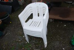 Four white plastic Patio chairs.