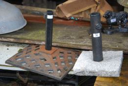 A cast iron parasol stand and a granite based stand.