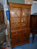 A contemporary Yew wood finished bookcase over cupboard,