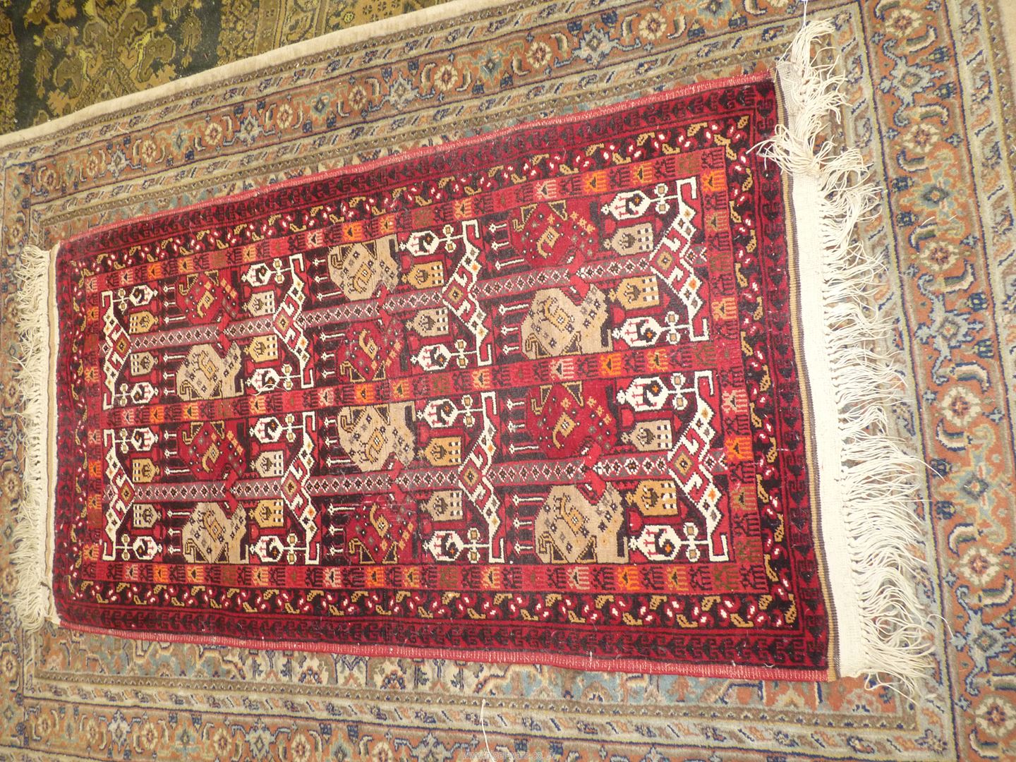 A border pattern and fringed Afghan tribal rug in bright and warm shades of terracotta, 58'' x 29''.