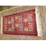 A border pattern and fringed Afghan tribal rug in bright and warm shades of terracotta, 58'' x 29''.