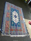 A bordered, patterned and fringed lightweight rug in bright Moorish colours with raised textures,
