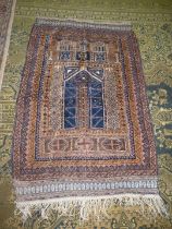 A Prayer rug in earth tones, brown and navy, 60'' x 35'' including fringe, some holes.