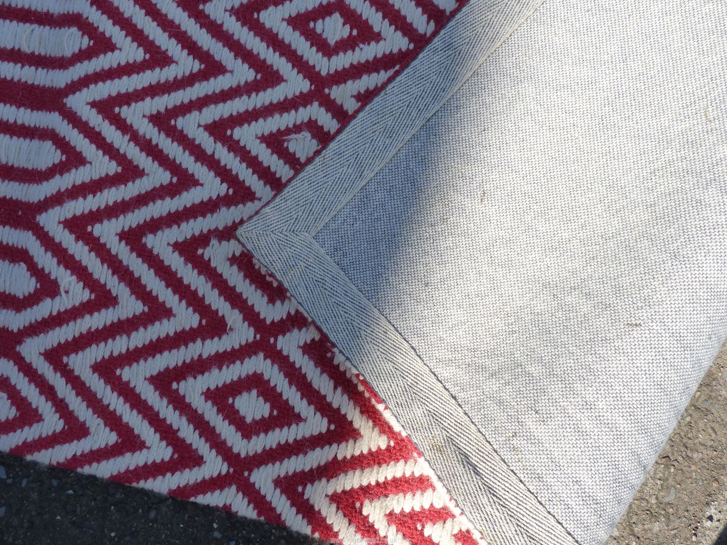 A red and white wool hearth rug, zig-zag and diamond patterns, 63" x 28", some stitching loose. - Image 3 of 3