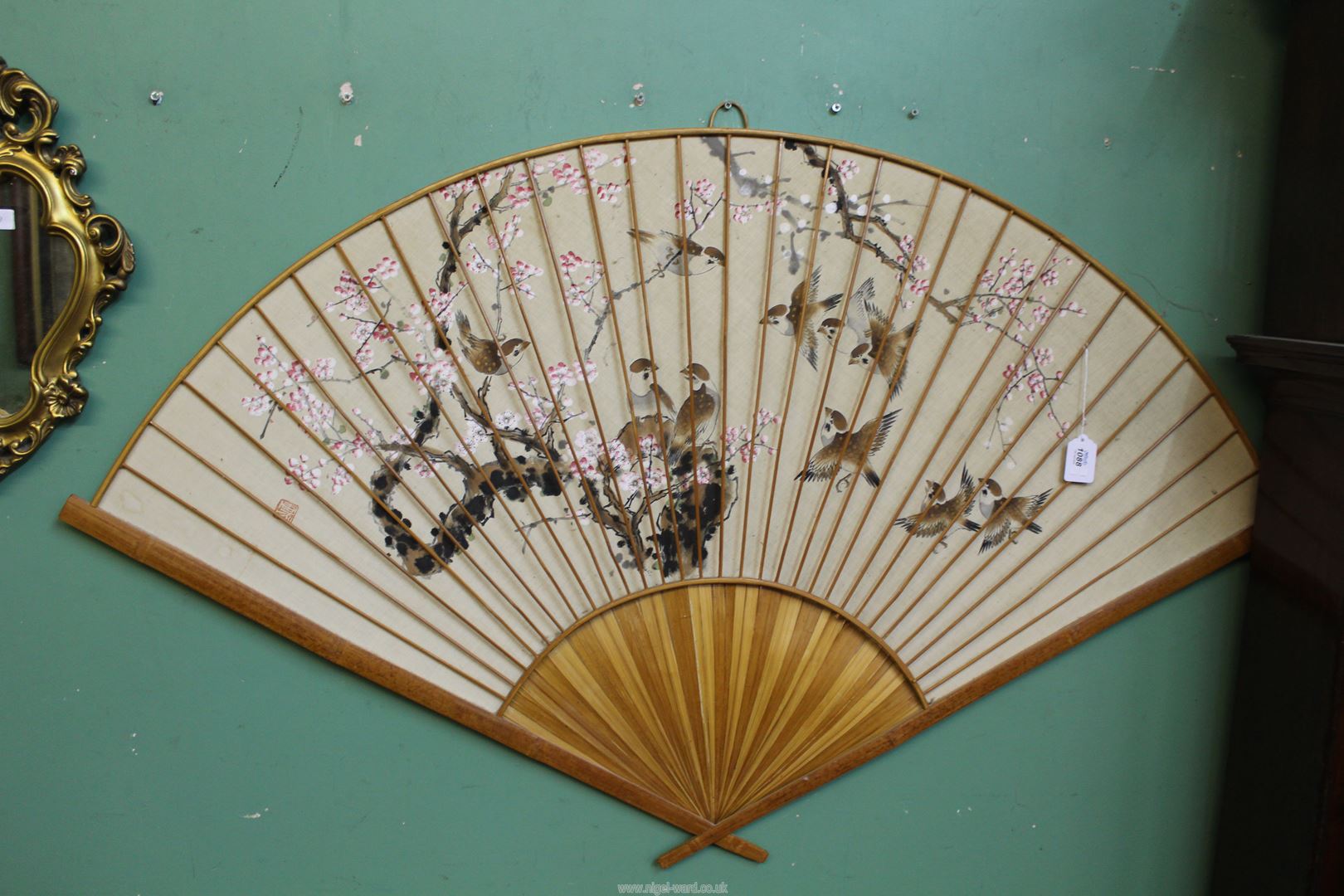 A very large hand painted Oriental Fan depicting sparrows and blossoms in a cane surround,