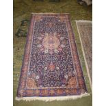 A border pattern and fringed rug with central gul on dark blue ground with all over stylised