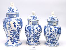 A trio of blue and white oriental floral ginger jar with lion head finials, some damage to lids,