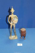 A small heavy cast metal model of an Owl and a brass figure of a tribesman beating a drum.