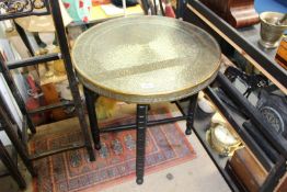 An early 20th century Benares brass top table with hammered design, on folding wooden base,